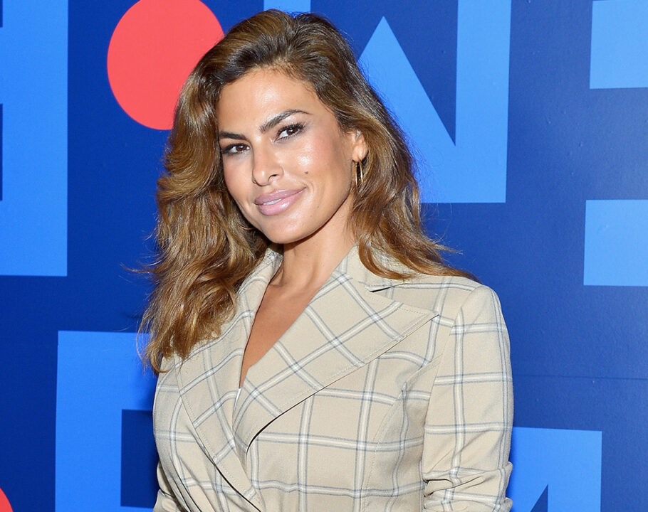 Eva Mendes in a beige plaid suit in front of a blue background