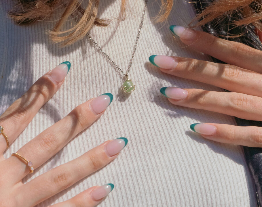 close up of manicured hands with green nail tips on woman's chest