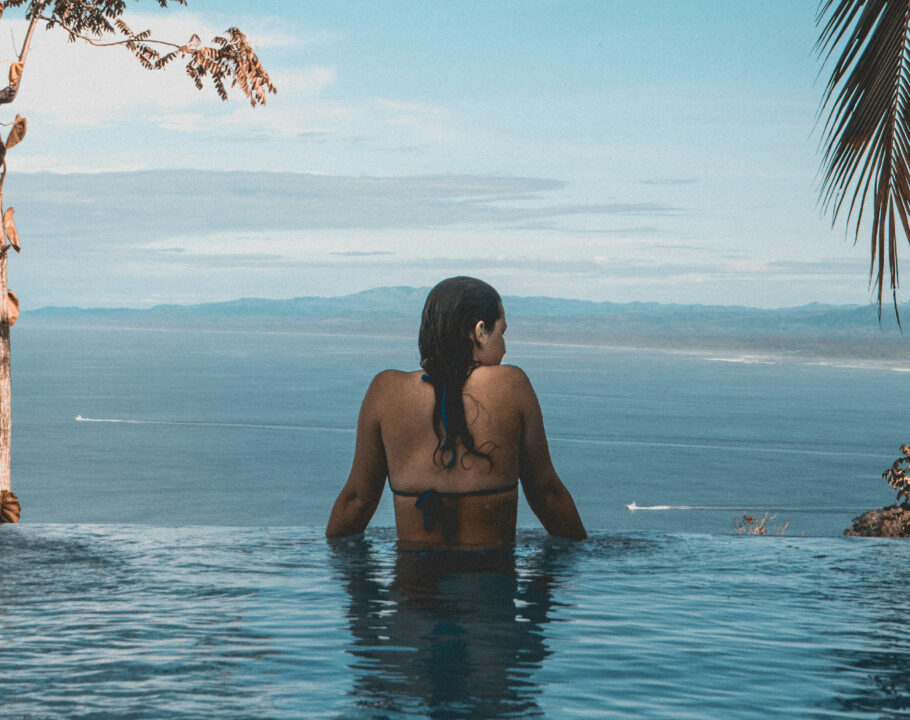 back view of woman in infinity pool looking out over ocean