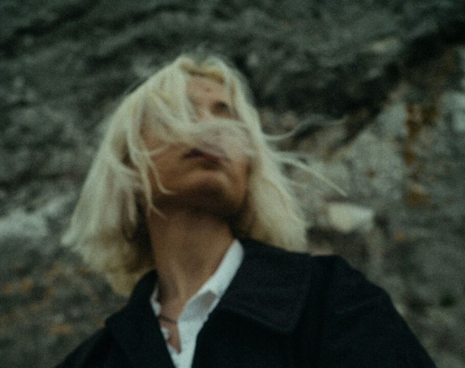 woman with short platinum blonde hair outside in black coat