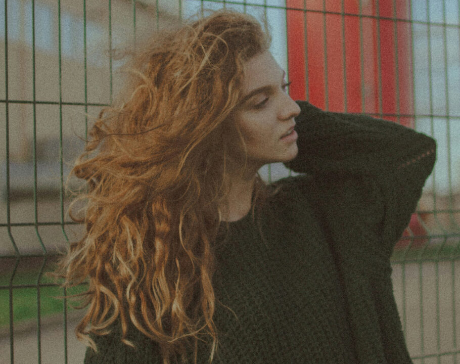 woman in black sweater with long red wavy hair