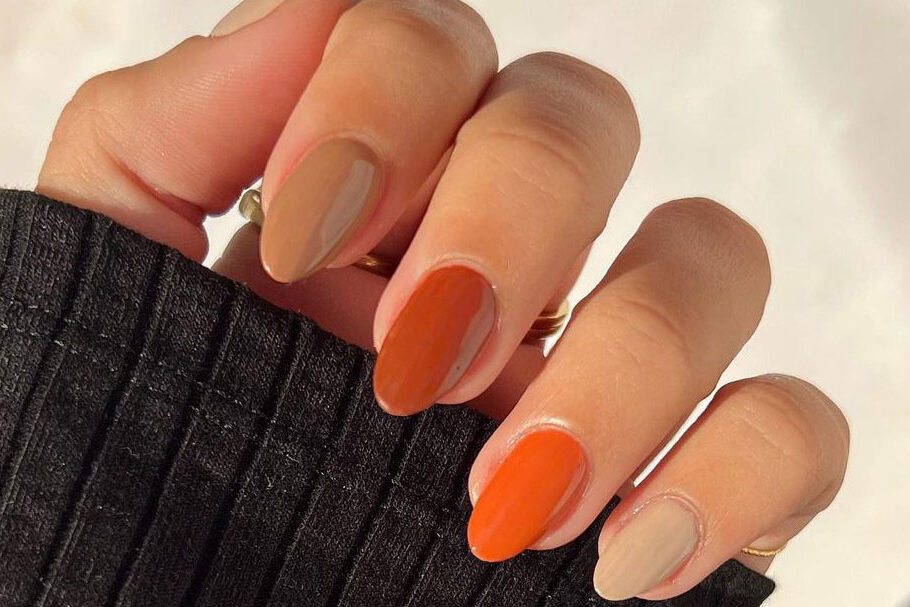 close-up of hands wearing brown and orange nail polishes