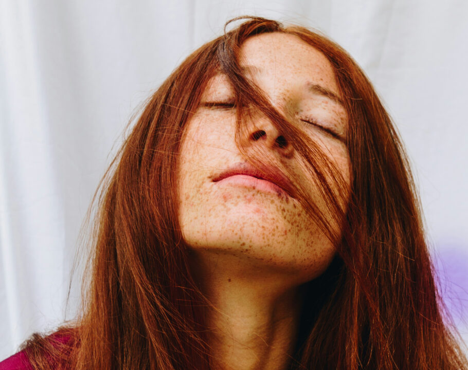 woman with red straight hair with eyes closed