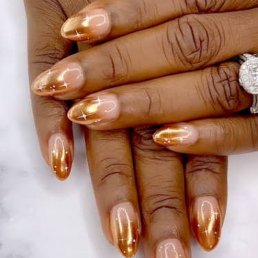 A close up of a woman's hands on top of each other showcasing her chrombre nails