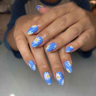 a close-up of blue nails with daisies