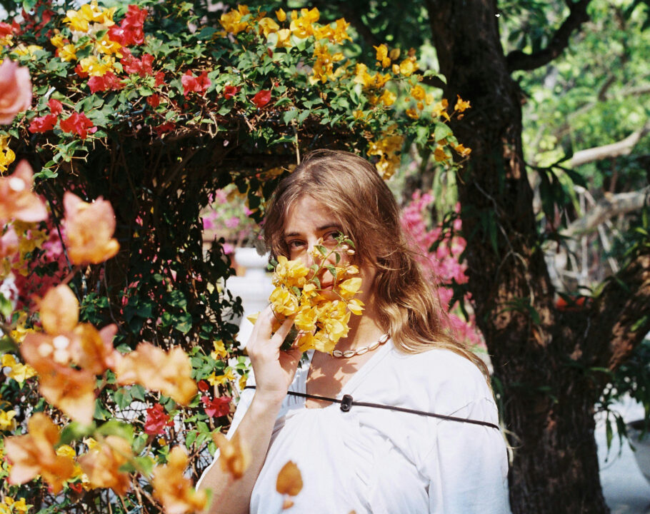 woman standing behind flowers on sunny day