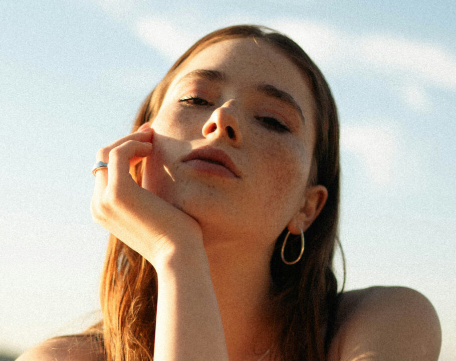 young woman's hand on face sitting in the sun