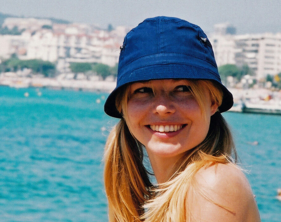 woman by the water smiling and wearing a bucket hat