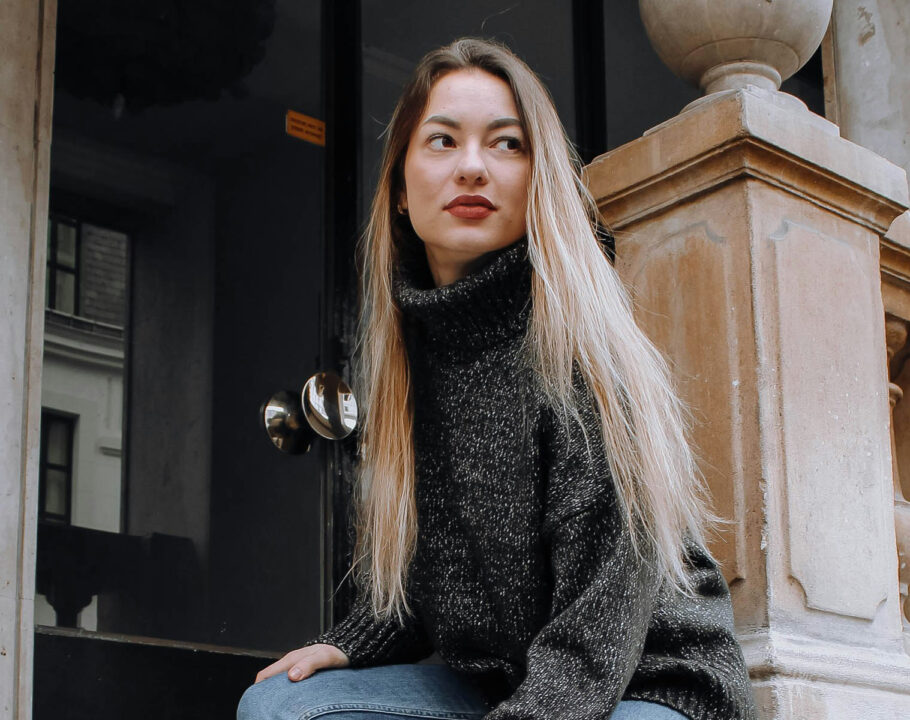 French woman with long blonde hair sitting outside in a city