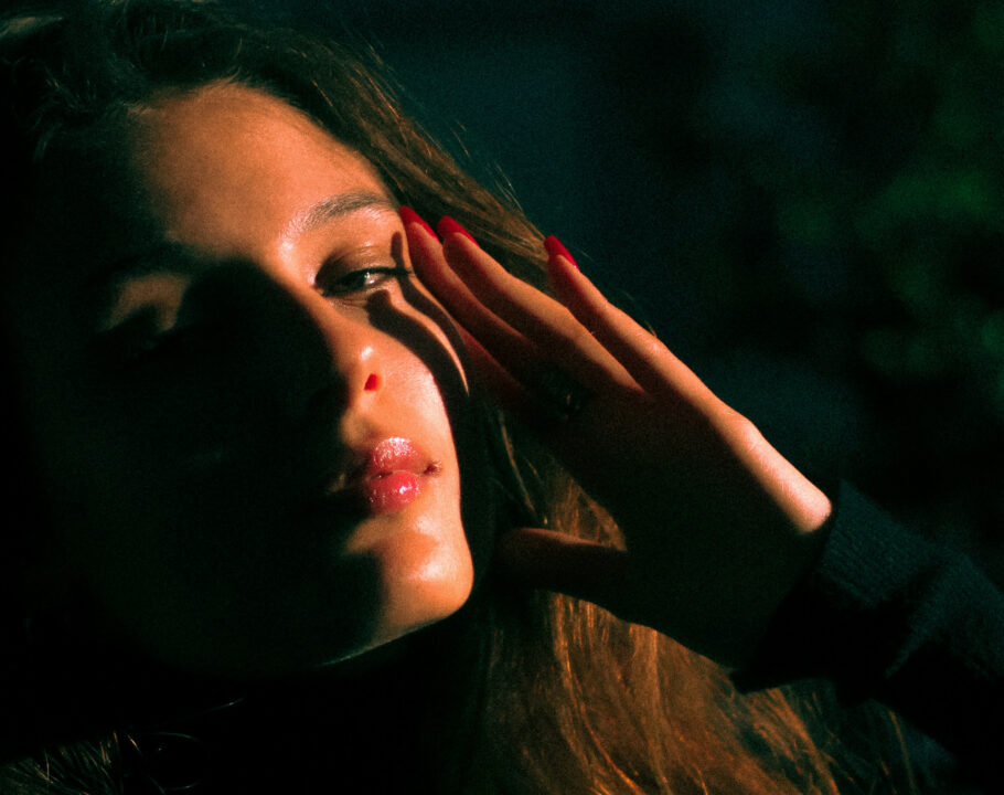 woman sitting in dark with hand on her face