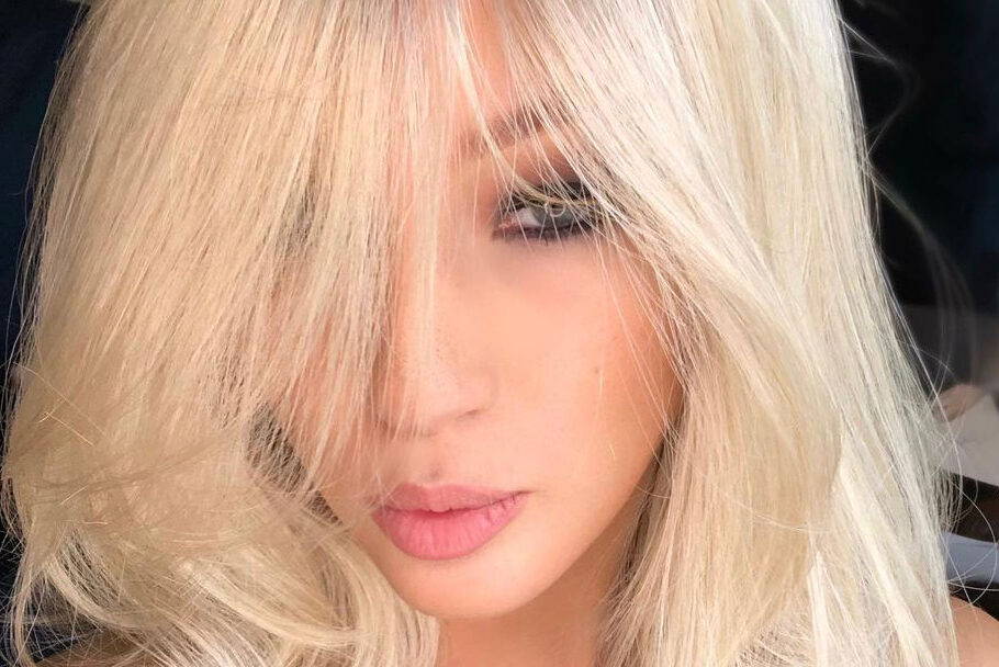 A close up of a woman's face with feathery, full hair and her bangs cascading by eyes