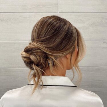 A low bun hairstyle with loose tendrils