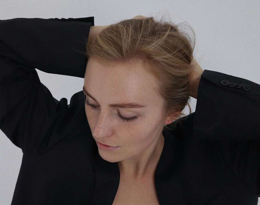 woman in black blazer putting her hair back