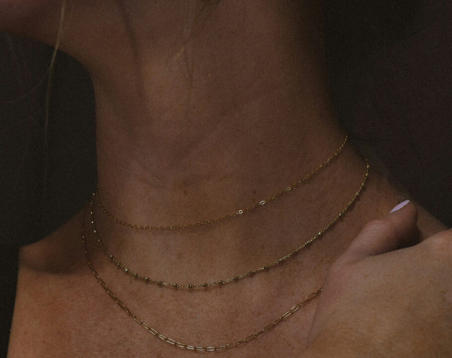 close up of woman's neck wearing dainty gold chains