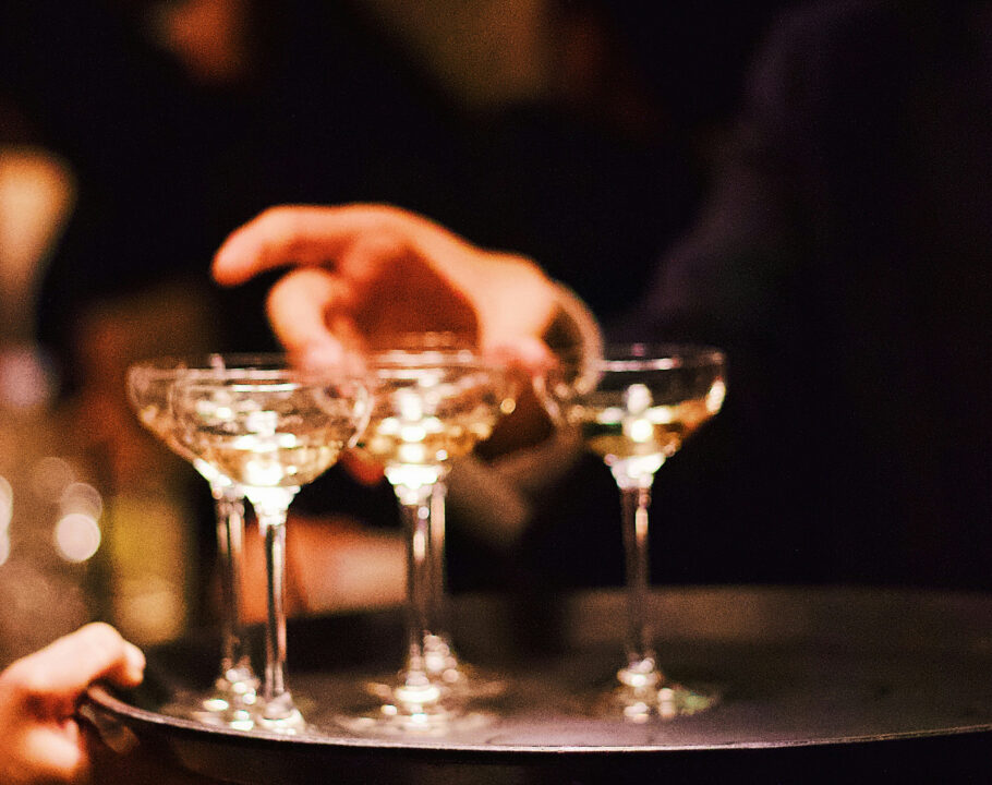 hand grabbing champagne glasses from a tray